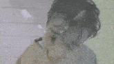 a man in a white shirt is making a funny face in front of a tiled wall .