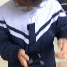 a person wearing glasses and a blue and white jacket is holding a black object