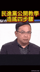 a man wearing glasses and a suit stands in front of a sign with chinese writing on it