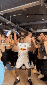 a man in a white red bull jersey is dancing in front of a crowd