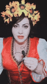 a woman wearing a flower crown and a red dress holds a microphone