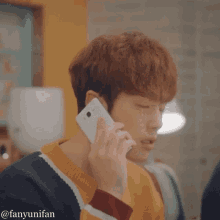 a young man is talking on a cell phone while wearing a colorful sweater ..