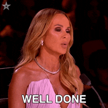a woman in a pink dress is sitting in front of a microphone with the words well done written on her face