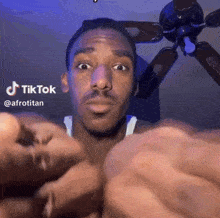 a man is making a funny face in front of a ceiling fan with tiktok written on it