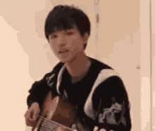a young man is playing a guitar in a room and making a funny face .