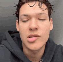 a close up of a young man 's face with his eyes closed and his tongue out .