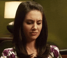a woman with dark hair is wearing a purple floral shirt