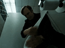 a man in a black suit is holding a roll of toilet paper in his hand