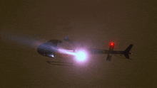 a helicopter with a red light on the tail is flying in the night sky