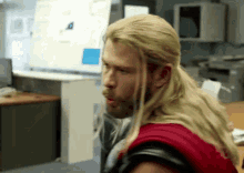 a man with long blonde hair and a beard is sitting in front of a computer screen