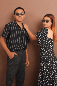 a man in a striped shirt stands next to a woman in a dress