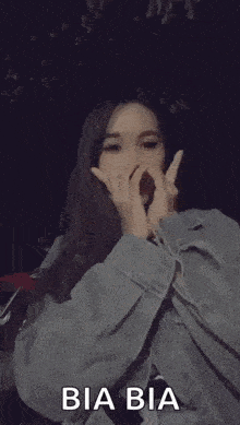 a woman in a denim jacket is making a heart with her hands .