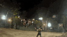 a man in a batman costume is standing in front of a crowd of people at night