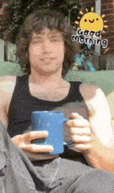 a man in a black tank top is holding a blue mug with a good morning sticker on it
