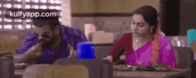 a man and a woman are sitting at a table in a restaurant and eating food .