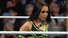 a woman in a green and black outfit is in a wrestling ring with the letters n on the screen behind her