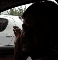 a man is smoking a cigarette while sitting in the driver 's seat of a car