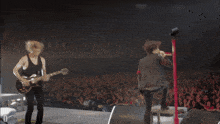 a man singing into a microphone while another man plays guitar