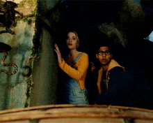 a woman in overalls is standing next to a man