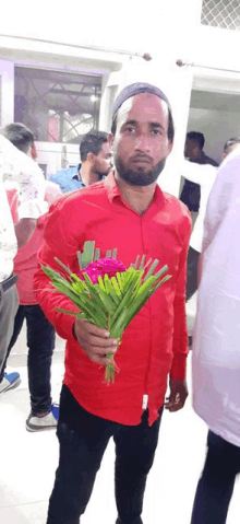 a man in a red shirt holds a bouquet of flowers in his hand