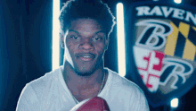 a man holds a football in front of a ravens emblem