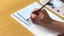 a person is painting on a piece of paper with the words made in animatica visible