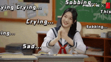 a girl in a school uniform is sitting at a desk in front of a blackboard that says sobbing
