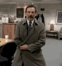 a man in a suit and tie is standing in a room .
