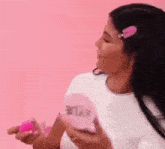 a woman in a white shirt is holding a pink item in her hand .