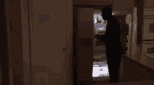 a man is standing in a dark room looking into a refrigerator .
