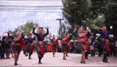 a group of people are dancing in a parade in a street