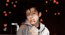 a young man is surrounded by hearts flying around his face .