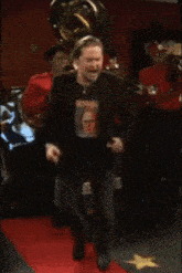 a man wearing a shirt that says ' jesus ' on it is dancing on a red carpet