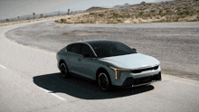 a white kia car is driving down a curvy road