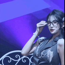 a woman wearing glasses and a microphone has the letter m on her headband