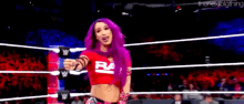 a female wrestler with purple hair is standing in a wrestling ring .