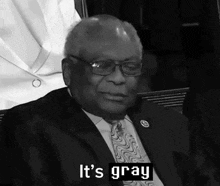 a man in a suit and tie says " it 's gray " in a black and white photo