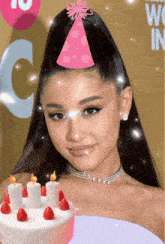 a woman wearing a pink party hat holds a cake