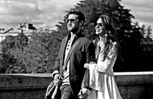 a man and a woman are standing next to each other on a bridge and holding hands .