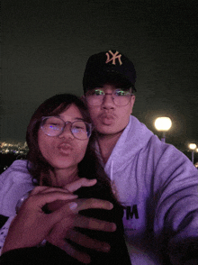 a man wearing a ny yankees hat kisses a woman