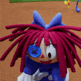 a stuffed doll with pink dreadlocks and a blue button on her eye