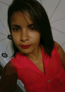 a woman in a red top takes a selfie with a geometric pattern in the background