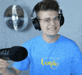 a man wearing headphones and a blue shirt that says lonely is holding a microphone