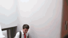 a man in a suit and tie is leaning against a wall while walking down stairs .