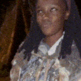 a young girl with dreadlocks is wearing a floral jacket
