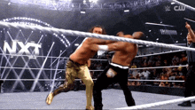 two men are wrestling in a ring with nxt written on the wall