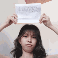 a girl holds a piece of paper that says i love you