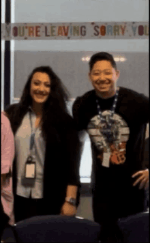 two people standing in front of a sign that says you 're leaving sorry you