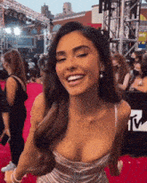 a woman is smiling on a red carpet while wearing a plunging neckline dress .