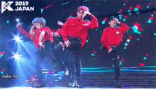 a group of men are dancing on a stage in front of a sign that says ' i make me ' .